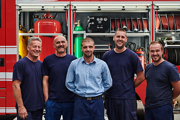 Image showing A skilled and dedicated professional firefighting team proudly poses in front of their state of the art firetruck, showcasing their modern equipment and commitment to ensuring public safety.