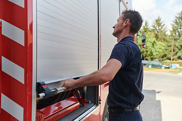 Image showing A dedicated firefighter preparing a modern firetruck for deployment to hazardous fire-stricken areas, demonstrating readiness and commitment to emergency response