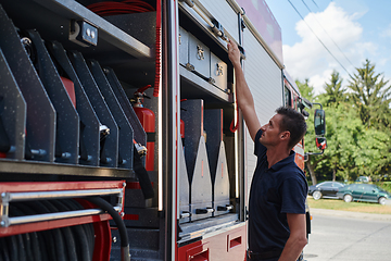 Image showing A dedicated firefighter preparing a modern firetruck for deployment to hazardous fire-stricken areas, demonstrating readiness and commitment to emergency response