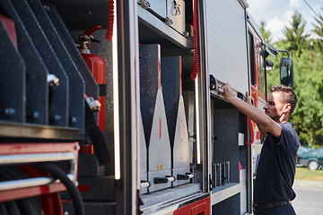 Image showing A dedicated firefighter preparing a modern firetruck for deployment to hazardous fire-stricken areas, demonstrating readiness and commitment to emergency response