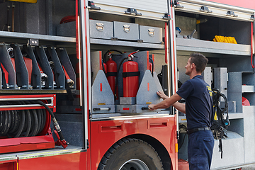 Image showing A dedicated firefighter preparing a modern firetruck for deployment to hazardous fire-stricken areas, demonstrating readiness and commitment to emergency response