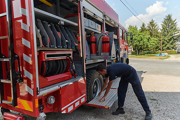 Image showing A dedicated firefighter preparing a modern firetruck for deployment to hazardous fire-stricken areas, demonstrating readiness and commitment to emergency response