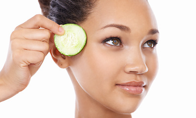 Image showing Woman, face and cucumber by eyes in skincare, beauty or facial and spa treatment against a white studio background. Closeup of female person or model with natural organic vegetables for wellness