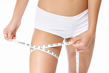 Image showing Woman, legs and tape measure for diet, weight loss or slim body in health and wellness on a white studio background. Closeup of female person or model hands measuring thigh in fitness or healthcare