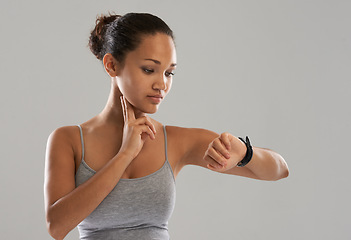 Image showing Woman, watch and checking pulse on neck for monitoring heartbeat against a gray studio background. Active female person or athlete looking at wristwatch in fitness for blood pressure on mockup space