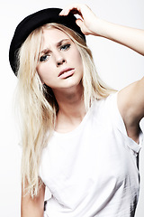 Image showing Woman, portrait and fashion in studio, hat and serious with makeup by white background. Female model person, casual clothing and vintage style and face, funky and confidence or frown by backdrop