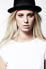 Image showing Woman, portrait and edgy fashion in studio, hat and eyeliner or makeup by white background. Female model person, casual clothing and vintage style and face, funky and confidence or pride by backdrop