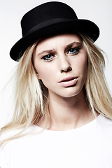 Image showing Woman, portrait and fashion in studio, attitude and eyeliner or makeup by white background. Female model person, casual clothing and vintage style and face, hat and confidence or pride by backdrop