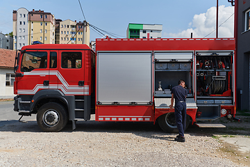 Image showing A dedicated firefighter preparing a modern firetruck for deployment to hazardous fire-stricken areas, demonstrating readiness and commitment to emergency response