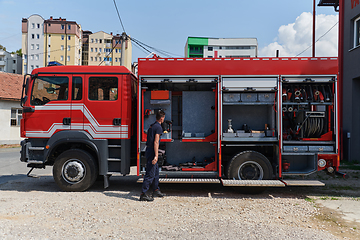 Image showing A dedicated firefighter preparing a modern firetruck for deployment to hazardous fire-stricken areas, demonstrating readiness and commitment to emergency response