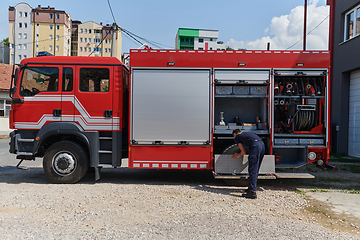 Image showing A dedicated firefighter preparing a modern firetruck for deployment to hazardous fire-stricken areas, demonstrating readiness and commitment to emergency response