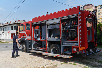 Image showing A dedicated firefighter preparing a modern firetruck for deployment to hazardous fire-stricken areas, demonstrating readiness and commitment to emergency response