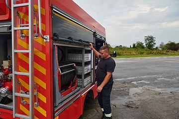 Image showing A dedicated firefighter preparing a modern firetruck for deployment to hazardous fire-stricken areas, demonstrating readiness and commitment to emergency response