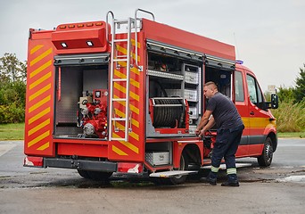 Image showing A dedicated firefighter preparing a modern firetruck for deployment to hazardous fire-stricken areas, demonstrating readiness and commitment to emergency response