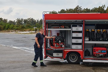 Image showing A dedicated firefighter preparing a modern firetruck for deployment to hazardous fire-stricken areas, demonstrating readiness and commitment to emergency response