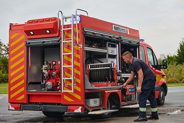 Image showing A dedicated firefighter preparing a modern firetruck for deployment to hazardous fire-stricken areas, demonstrating readiness and commitment to emergency response