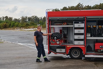 Image showing A dedicated firefighter preparing a modern firetruck for deployment to hazardous fire-stricken areas, demonstrating readiness and commitment to emergency response