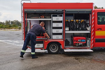 Image showing A dedicated firefighter preparing a modern firetruck for deployment to hazardous fire-stricken areas, demonstrating readiness and commitment to emergency response