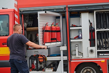 Image showing A dedicated firefighter preparing a modern firetruck for deployment to hazardous fire-stricken areas, demonstrating readiness and commitment to emergency response