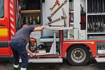 Image showing A dedicated firefighter preparing a modern firetruck for deployment to hazardous fire-stricken areas, demonstrating readiness and commitment to emergency response