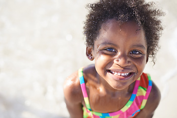Image showing Wet, happy child and portrait on beach sand, swimsuit and summer holiday with sunshine in nature. Black, young girl and smile face for swim on vacation, cape town and ocean for wellness in outdoor