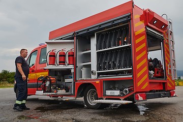 Image showing A dedicated firefighter preparing a modern firetruck for deployment to hazardous fire-stricken areas, demonstrating readiness and commitment to emergency response