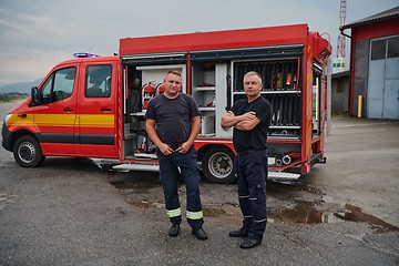 Image showing A skilled and dedicated professional firefighting team proudly poses in front of their state of the art firetruck, showcasing their modern equipment and commitment to ensuring public safety.