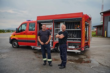 Image showing A skilled and dedicated professional firefighting team proudly poses in front of their state of the art firetruck, showcasing their modern equipment and commitment to ensuring public safety.