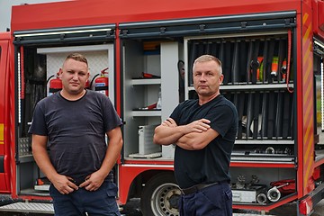 Image showing A skilled and dedicated professional firefighting team proudly poses in front of their state of the art firetruck, showcasing their modern equipment and commitment to ensuring public safety.