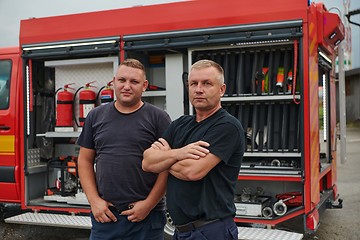 Image showing A skilled and dedicated professional firefighting team proudly poses in front of their state of the art firetruck, showcasing their modern equipment and commitment to ensuring public safety.