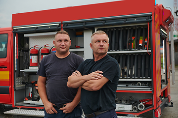 Image showing A skilled and dedicated professional firefighting team proudly poses in front of their state of the art firetruck, showcasing their modern equipment and commitment to ensuring public safety.