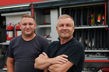 Image showing A skilled and dedicated professional firefighting team proudly poses in front of their state of the art firetruck, showcasing their modern equipment and commitment to ensuring public safety.