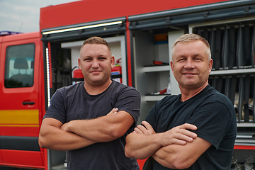 Image showing A skilled and dedicated professional firefighting team proudly poses in front of their state of the art firetruck, showcasing their modern equipment and commitment to ensuring public safety.