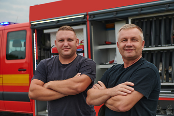 Image showing A skilled and dedicated professional firefighting team proudly poses in front of their state of the art firetruck, showcasing their modern equipment and commitment to ensuring public safety.