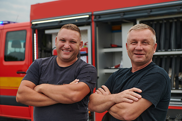 Image showing A skilled and dedicated professional firefighting team proudly poses in front of their state of the art firetruck, showcasing their modern equipment and commitment to ensuring public safety.