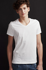 Image showing Man, model and portrait with fashion, modern style and cool outfit in dark studio or black background. Skinny male person, gen z and stylish clothes in confidence with tshirt of fashionable student