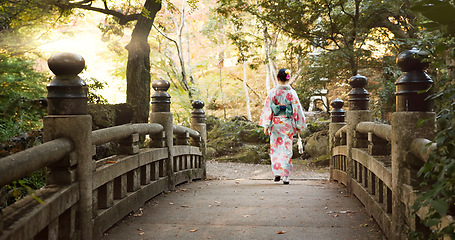 Image showing Bridge, culture and Japanese woman in park for wellness, fresh air and walking in nature. Travel, traditional and person in indigenous clothes, fashion and kimono outdoors for zen, calm and peace