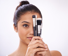 Image showing Cosmetics, brushes and woman cover eyes in studio for beauty, foundation and makeup on a white background. Young model, artist or person with skincare, application tools or product for face coverage