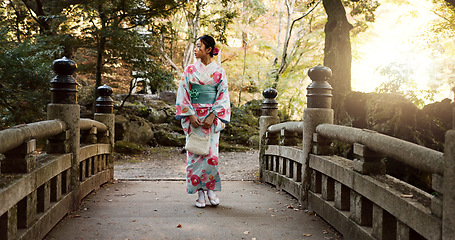 Image showing Bridge, traditional and Japanese woman in park for walking, fresh air and relax outdoors. Travel, culture and person thinking, wonder and calm in indigenous clothes, fashion and kimono on holiday