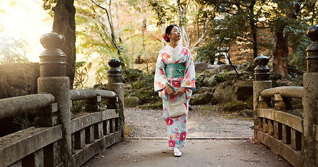 Image showing Walking, traditional and Japanese woman in park for calm, fresh air and relax on bridge outdoors. Travel, culture and person in indigenous clothes, style and kimono on holiday, peace or thinking