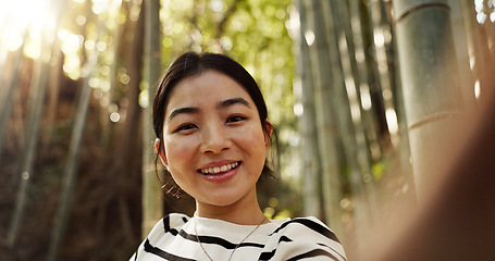 Image showing Japanese woman, portrait and selfie in forest with smile, pride and bamboo in bush for post on web blog. Girl, person and happy influencer on adventure, trekking or hiking by trees for social media