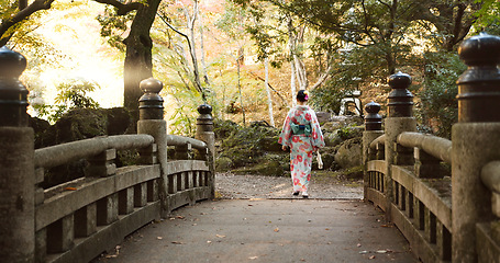 Image showing Bridge, walking and Japanese woman in park for wellness, fresh air and relaxing in nature. Travel, traditional and person in indigenous clothes, fashion and kimono outdoors for zen, calm and peace