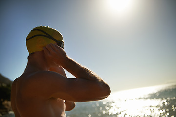 Image showing Sea, beach sunset and man for swimmer exercise, workout or outdoor training in ocean, nature or water. Mockup space, swimming cap and athlete ready to start challenge, fitness competition or cardio