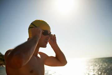 Image showing Sports, beach and man for swimming exercise, nature workout or outdoor practice in ocean, sea or water waves. Mockup sky space, goggles and swimmer for challenge, fitness performance or summer cardio