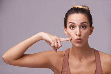 Image showing Portrait, beauty and finger on cheek with woman in studio on gray background for dermatology or cosmetics. Face, skincare and spa with natural young person pointing to mouth for wellness or facial