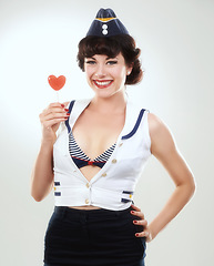 Image showing Portrait, smile of woman and sailor with lollipop in studio isolated on a white background. Face, candy and happy air hostess with sugar food, heart sweets and travel dessert for vintage pin up girl