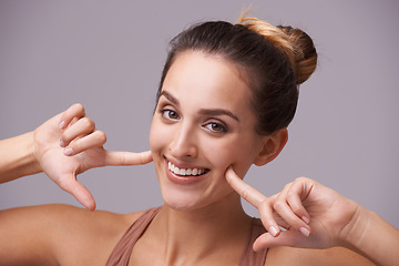 Image showing Portrait, smile and woman pointing at cheeks in studio isolated on purple background. Face, hands on skin or fingers of happy girl, natural model or beauty of person with gesture of facial expression