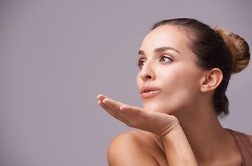 Image showing Skincare, kiss and young woman in a studio with health, wellness and dermatology routine. Cosmetic, confident and female person with natural facial treatment and flirt gesture by gray background.