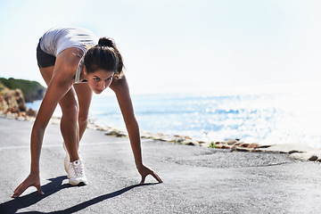 Image showing Woman, fitness and starting line by beach for running, workout or sprint in outdoor exercise. Active young female person getting ready for run, lap or cardio training on asphalt road by ocean coast