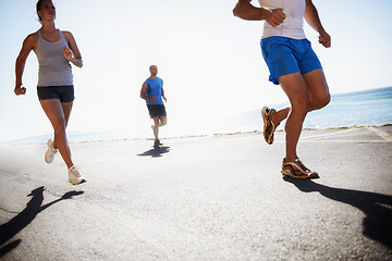 Image showing People, team and running at beach for cardio, fitness or outdoor workout together on asphalt or road. Athletic group or runners in sports, training exercise or street on sunny day by the ocean coast